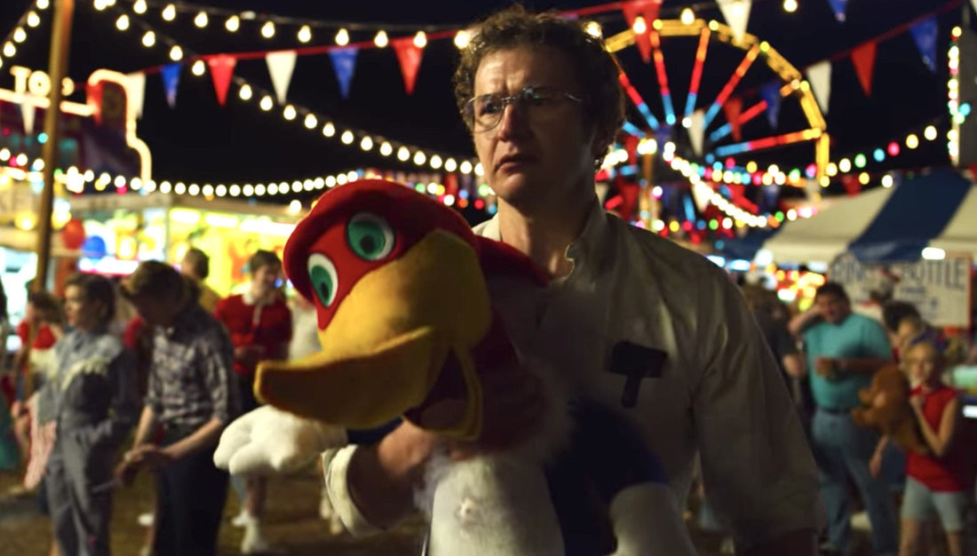 Alexei al luna park, un uccello di peluche tra le braccia, la ruota panoramica dietro.