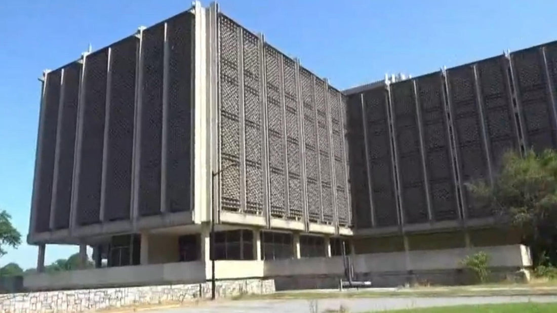 Grande edificio scolastico in cemento, visto dalla strada, sotto un cielo blu.