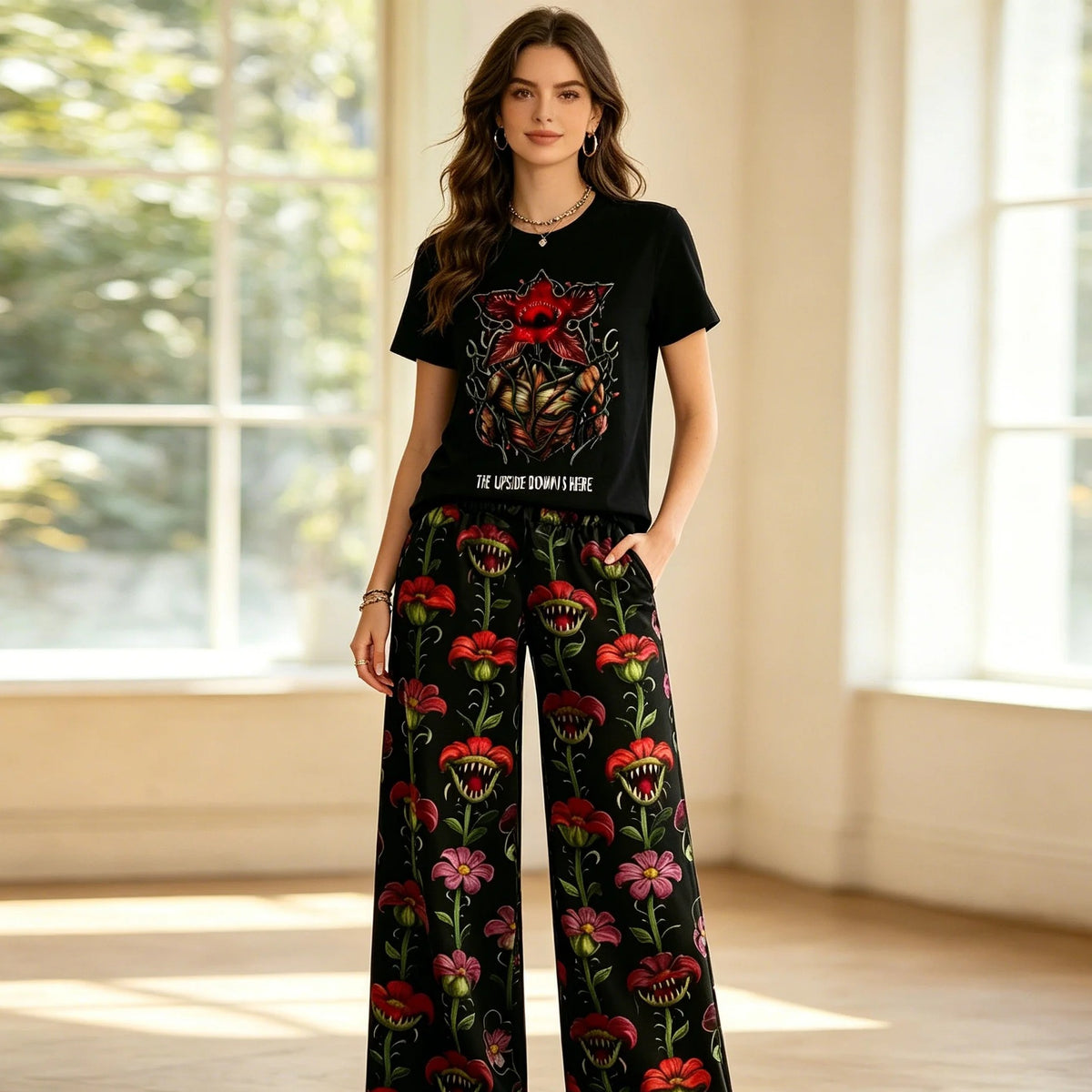 Donna che indossa il pigiama Stranger Things con t-shirt nera Demogorgone e pantaloni larghi a fiori